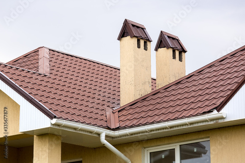 a brown rooftop of a ceramic tile with a pipe a storm drainage system, close up details of the architectural structure.