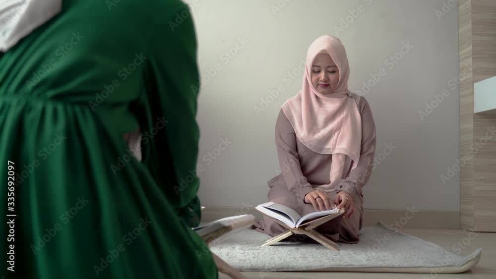 three asian moslem woman read and learn the holy book of the Al-Quran together sitting on the floor in the room three asian moslem woman read and learn the holy book of the Al-Quran together sitting on the floor in the room