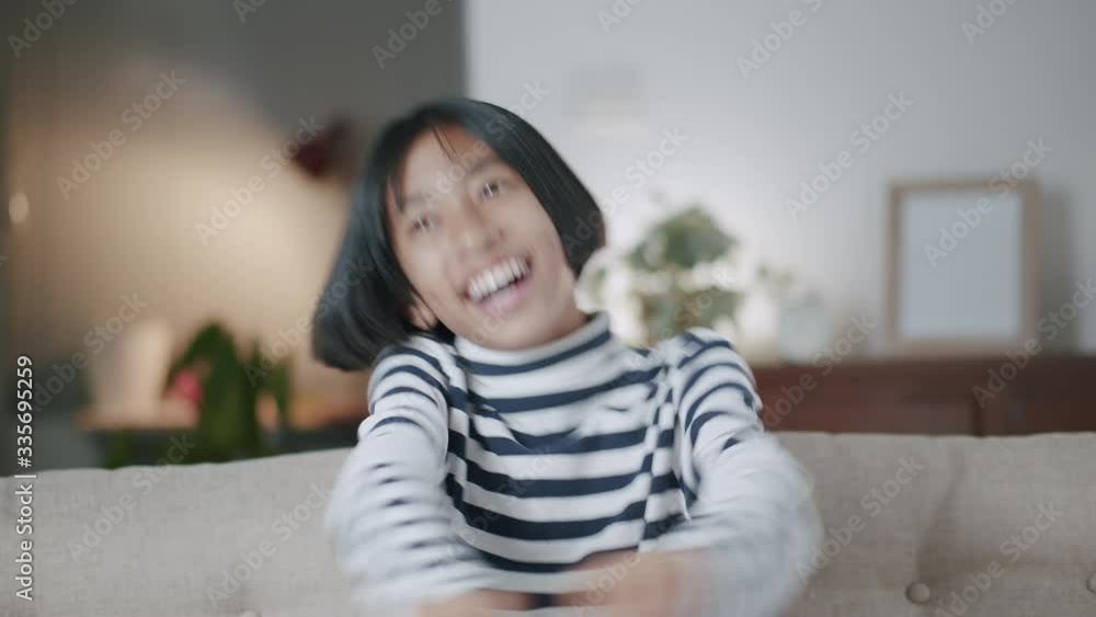 Happy Asian girl smile and dance with confidence while sitting on the sofa in the living room at home night, The Medium shot of Asia child on face expression and pose. relaxation lifestyle concept Happy Asian girl smile and dance with confidence while sitting on the sofa in the living room at home night, The Medium shot of Asia child on face expression and pose. relaxation lifestyle concept