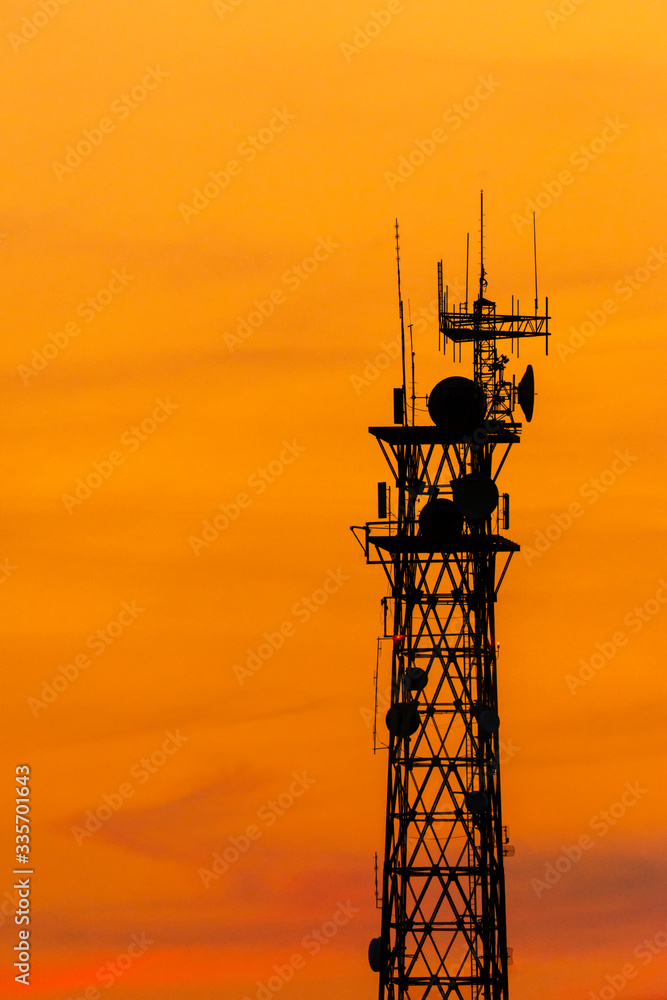 Cell towers, silhouette with sunset sky background, vertical composition with copy space.