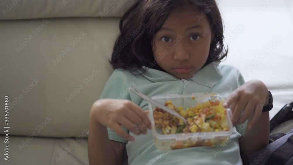 Unhappy little girl holding a lunchbox with salad Unhappy little girl holding a lunchbox with salad