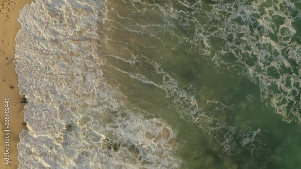 Aerial view looking directly down on a beach in the early morning light with waves crashing. Aerial view looking directly down on a beach in the early morning light with waves crashing.