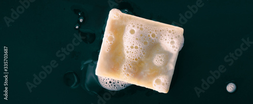 фотографія Bar of soap with foam bubbles on black background panoramic banner texture
