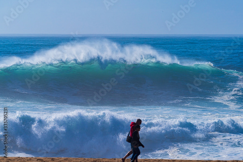 Giant breaking waves along the beach -Nazare North Beach, Portugal  is the most famous surfing spot in the world. Many people came to watch the highest breaking waves at the beach. 
