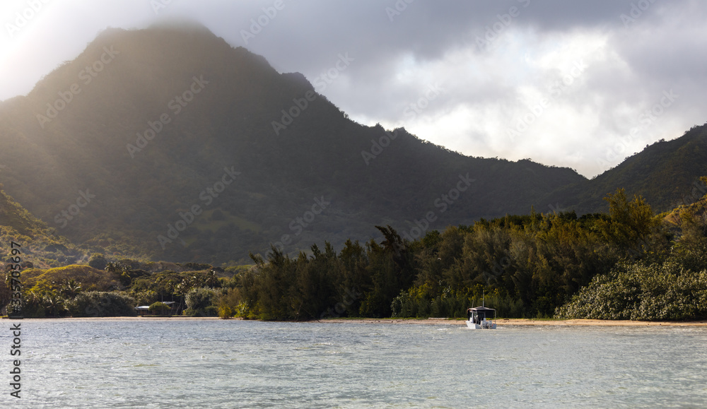 Boat going to mooring to the beach, with beautiful mountains and palm trees on background in sunny weather Hawaii paradise