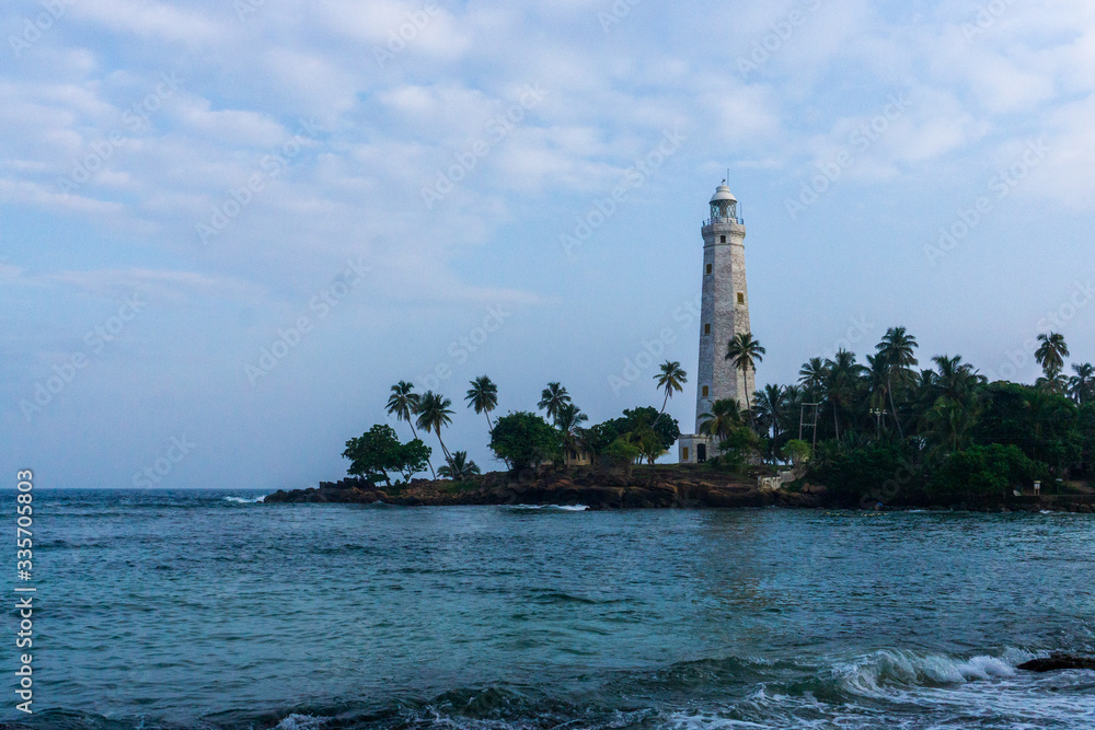 Lighthouse with coconut trees with a beach foreground