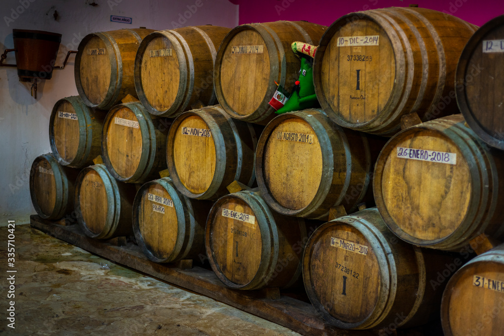 Stacked wooden barrels in Mexican tequila distillery.