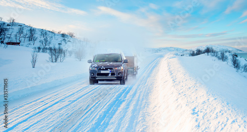 Car (SUV) moving on snowy road  with small trailer at the winter - Tromso, Norway © muratart