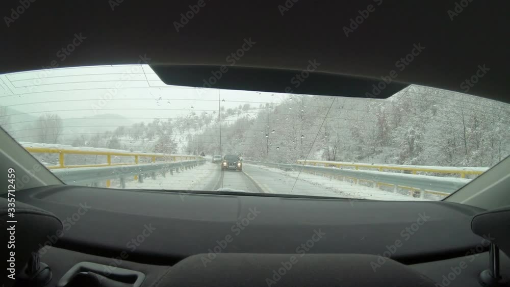 Car driving on snow-covered snowy mountain road in winter snow. Driver`s point of view viewpoint looking through rear windshield Car driving on snow-covered snowy mountain road in winter snow. Driver`s point of view viewpoint looking through rear windshield