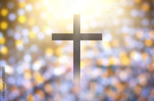The Christian cross looks bright in soft white and the glittering bokeh background is the light of hope and leads to heaven.