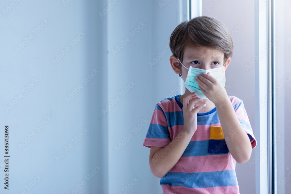 Young caucasian boy wearing a protection mask for prevent Corona virus or air pollution,Use your hands to tighten the mask tightly, environmental and healthy concept Young caucasian boy wearing a protection mask for prevent Corona virus or air pollution,Use your hands to tighten the mask tightly, environmental and healthy concept