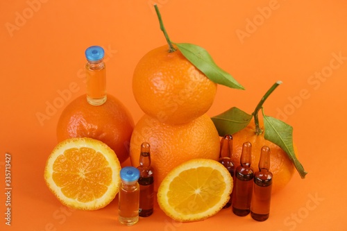 Vitamin C prevention of immunity from viruses.Vitamin C set of ampoules and fresh oranges and mandarin on a orange background.Serum with Vitamin C. Organic cosmetics concept. Medicine