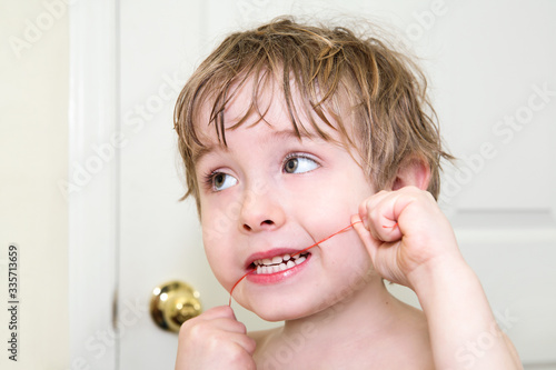 Young boy flossing his teeth, learning dental hygiene photo