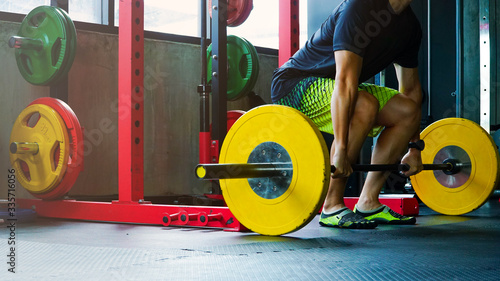 Young men prepare to perform deadlift exercises using 15 weights each in a cross-style gym.