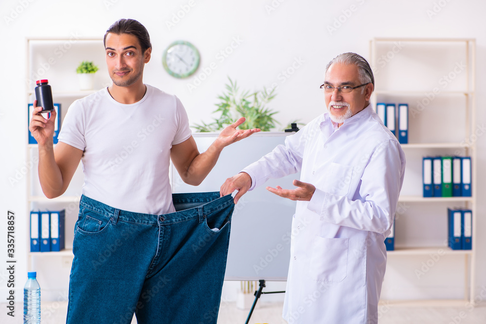 Fototapeta premium Doctor dietician and happy patient wearing large trousers