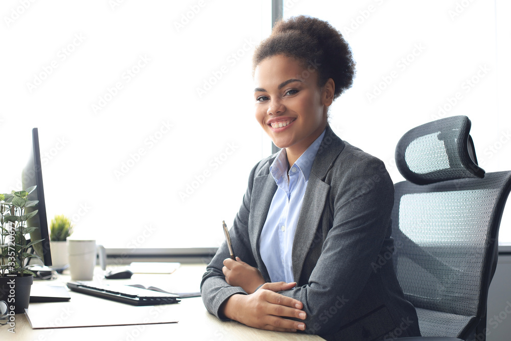Portrait of beautiful young african american woman working on computer while sitting at the table. Portrait of beautiful young african american woman working on computer while sitting at the table.