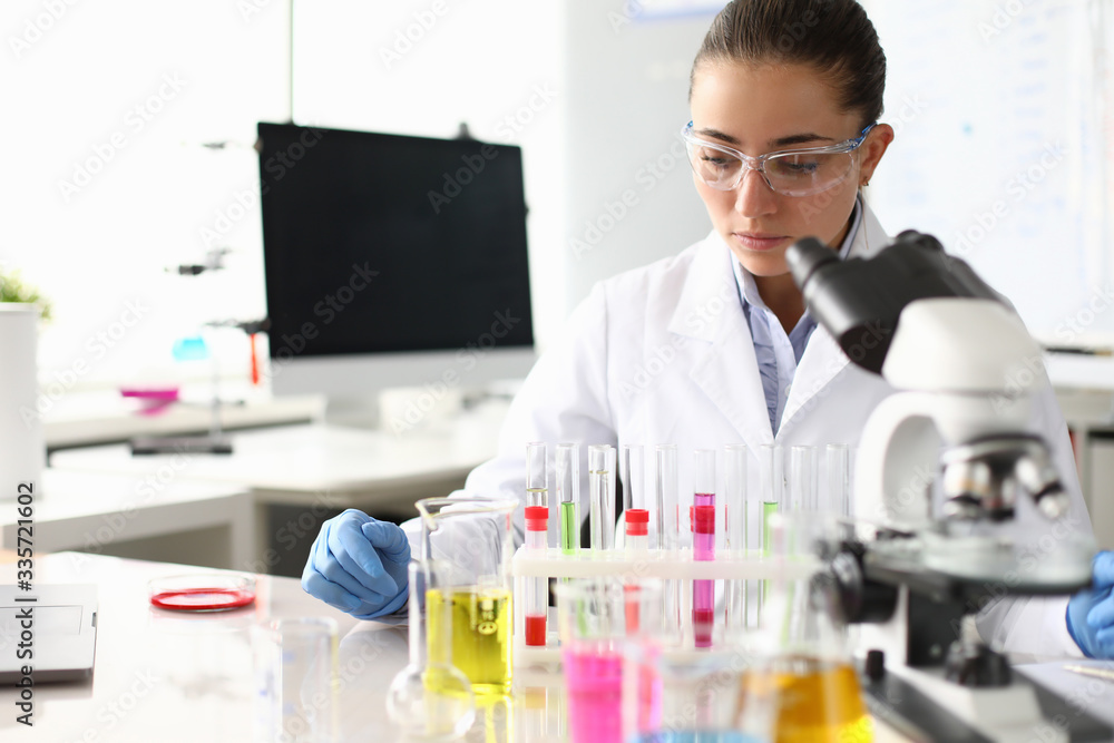 Portrait of concentrated scientist working with liquids in research laboratory. Researcher at workplace. Flasks, test-tubes, beakers on table. Chemical experiments concept