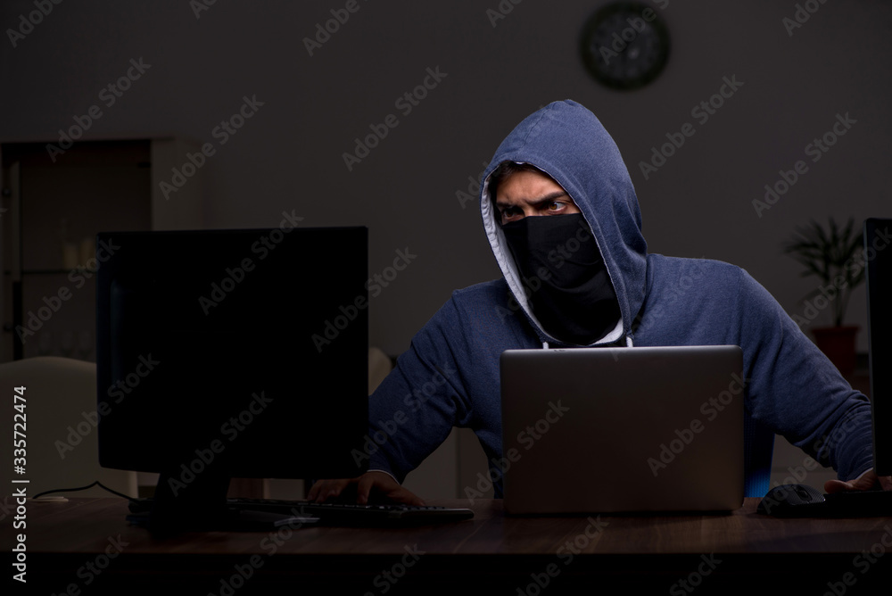 Male hacker hacking security firewall late in office Male hacker hacking security firewall late in office
