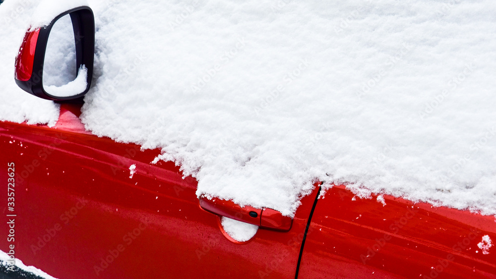 Fragment of a red car covered with white snow close-up