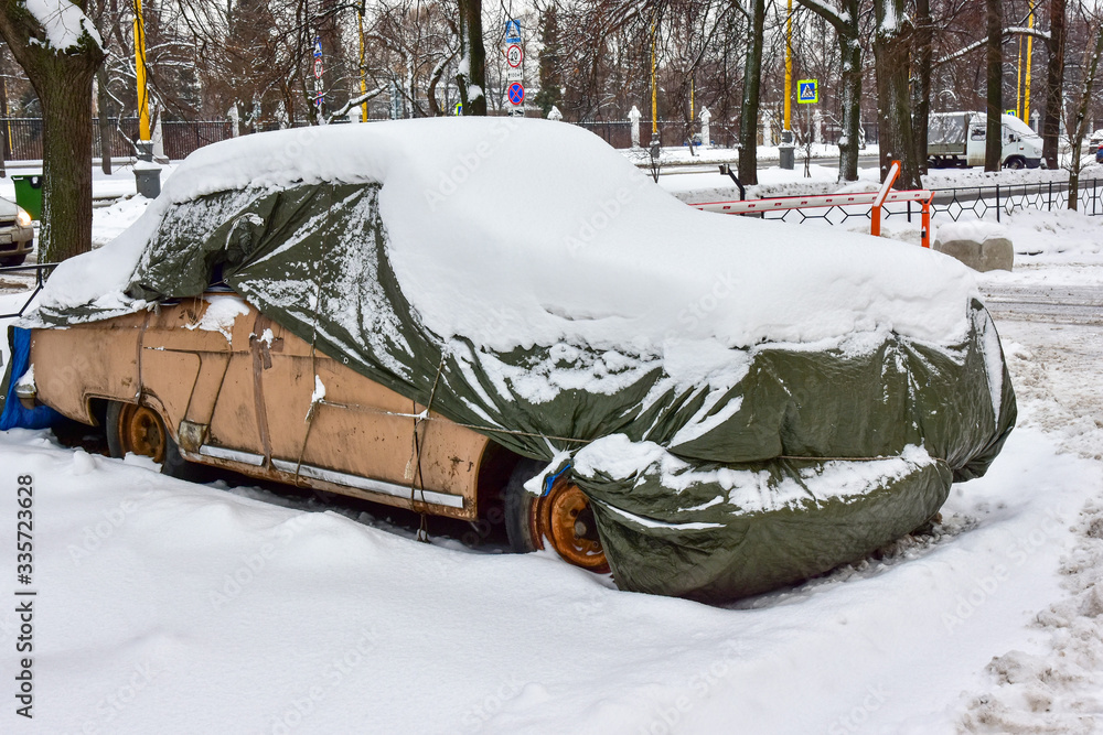 beige old car covered with case and white snow