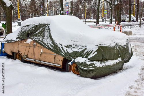 Obraz na płótnie beige old car covered with case and white snow w salonie