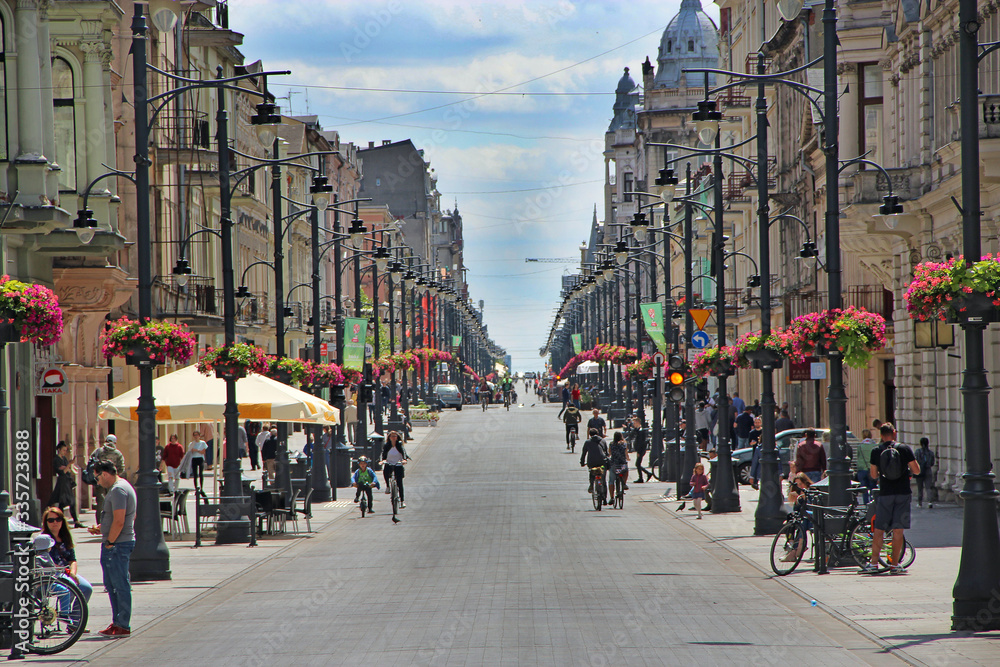 Obraz na płótnie View of city street with many flowers and people riding bicycles. City life w salonie