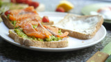 Cooking Toasts with avocado and smoked salmon on the white plate