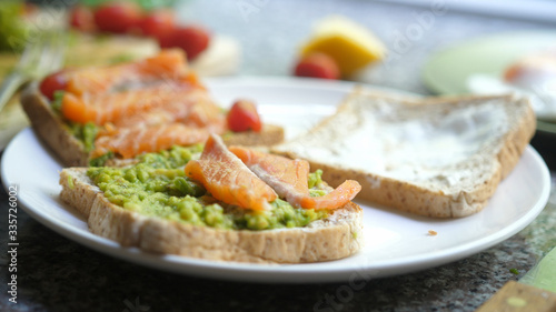Cooking Toasts with avocado and smoked salmon on the white plate
