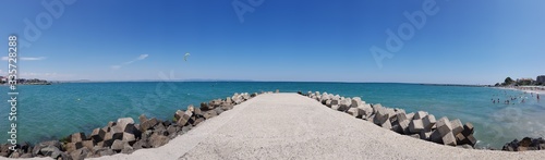 Panorama landscape view of pier covered with breakwaters around, which protects the beach and the city from strong waves. 