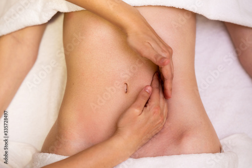 Woman receiving a belly massage in a physiotherapy center. © javiindy