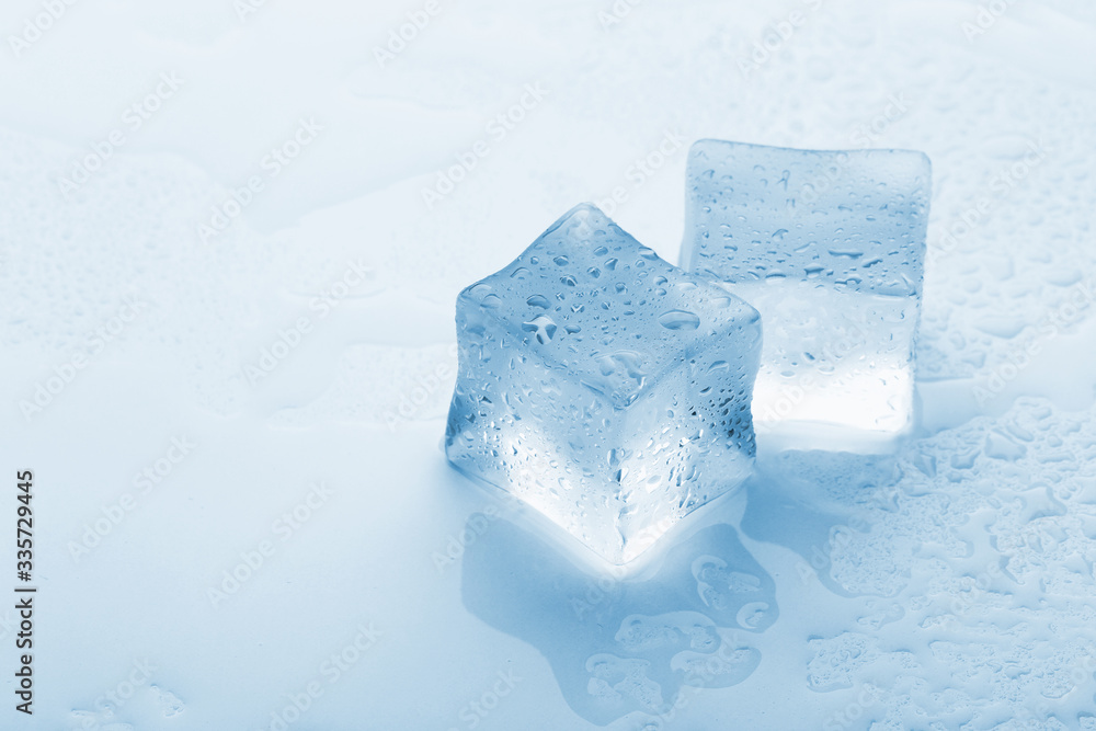 several melted ice cubes with drops on a light background with blue tinting several melted ice cubes with drops on a light background with blue tinting