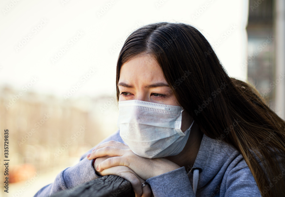 COVID-19 coronavirus pandemic. A woman in a medical mask sits at home in isolation to prevent the spread of a dangerous virus COVID-19 coronavirus pandemic. A woman in a medical mask sits at home in isolation to prevent the spread of a dangerous virus