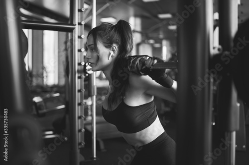 Foto Woman training in smith machine, monochrome.