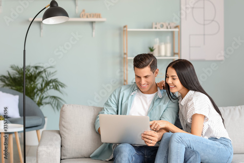 Happy young couple with lap...
