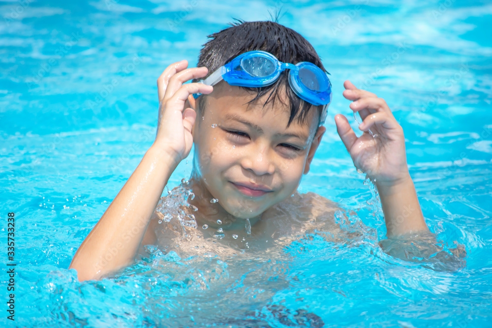 Portrait Asian boy wearing swimming goggles in the pool.