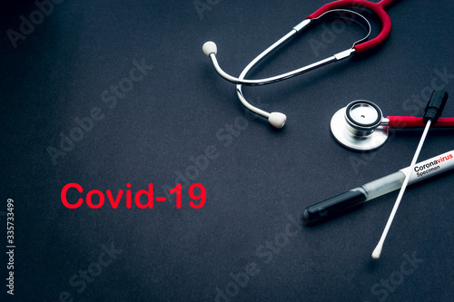 COVID-19 text with stethoscope and medical swabs on black background. Covid -19 or Coronavirus Concept