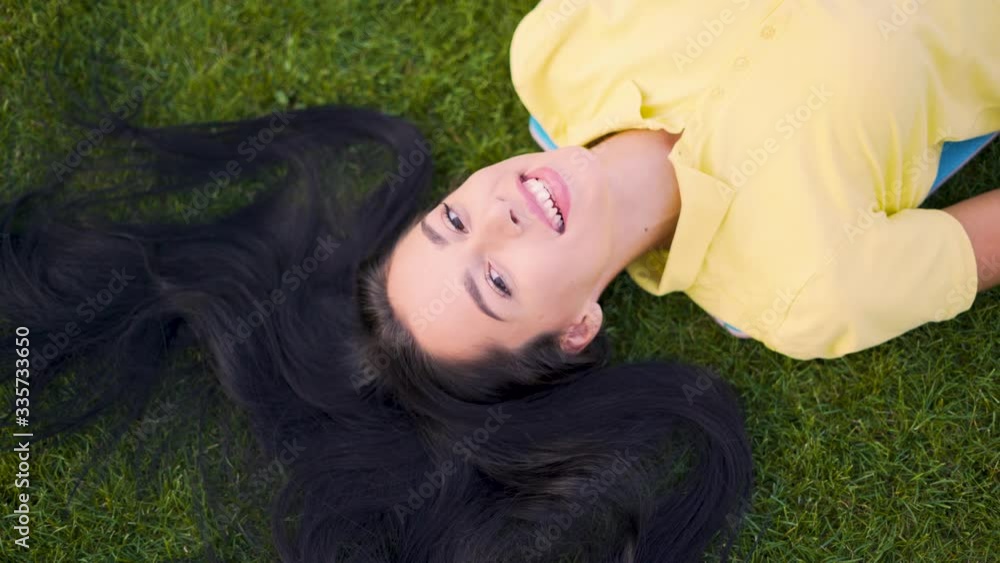 Smiling joyful girl in laughing lying on the grass and looking at the camera 4K Smiling joyful girl in laughing lying on the grass and looking at the camera 4K