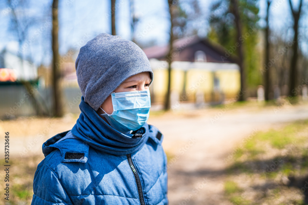 Plakat Child boy walking outdoor with face mask for protection. School boy breathing through medical mask. Coronovirus epidemic. COVID-19 and coronavirus identification. Pandemic.