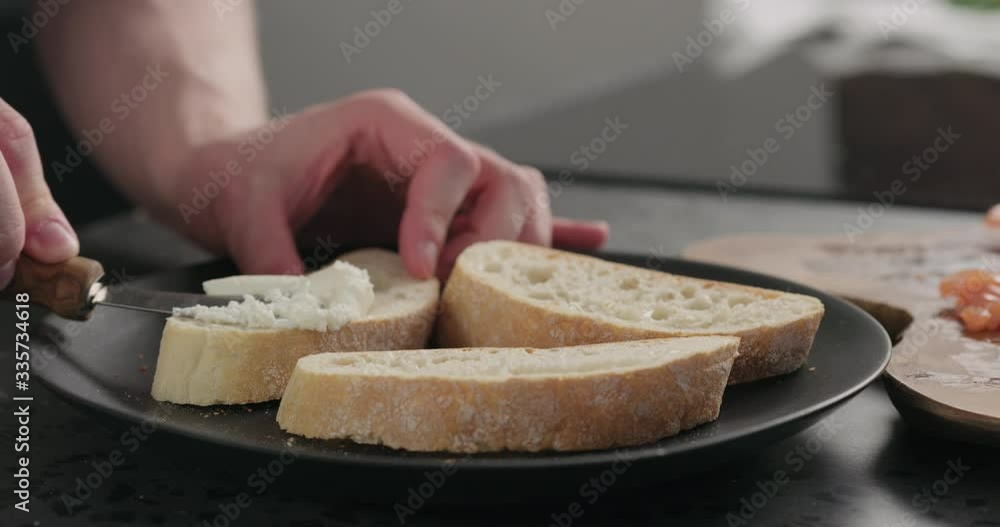 Slow motion man spread cream cheese on ciabatta slice on black plate Slow motion man spread cream cheese on ciabatta slice on black plate