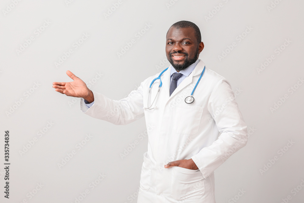 African-American doctor showing something on light background African-American doctor showing something on light background