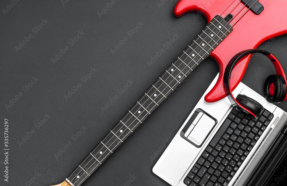 Obraz premium Electric guitar with laptop and headphones on black. Writing music. Top view. Space for text.
