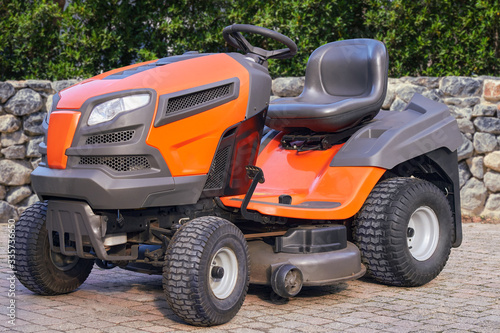 Shining orange lawn mower with seat ready for the job