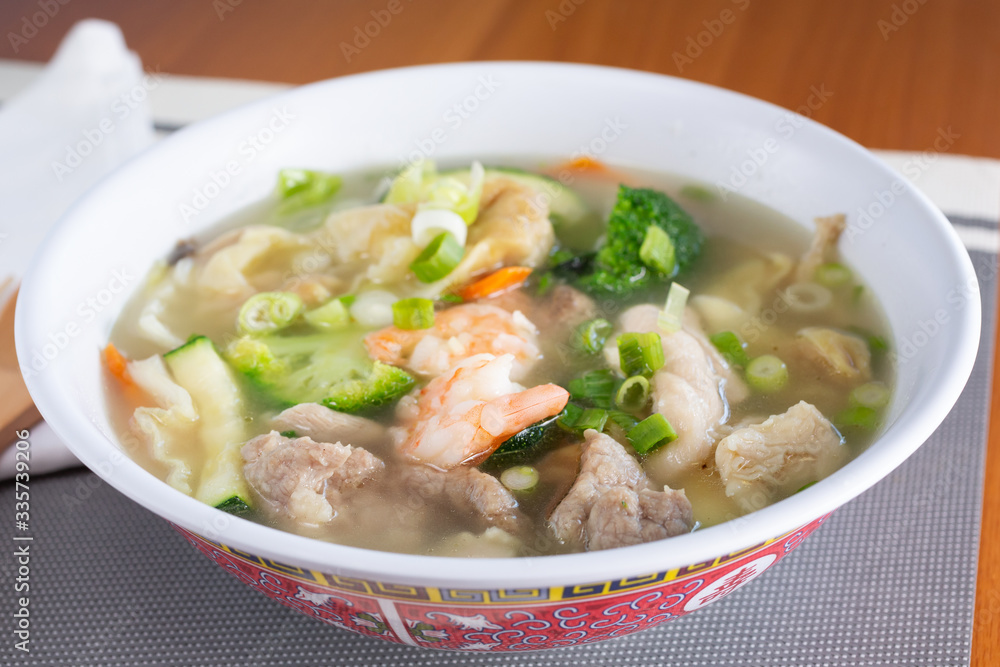 A view of a big bowl of Chinese wonton soup in a restaurant or kitchen setting.