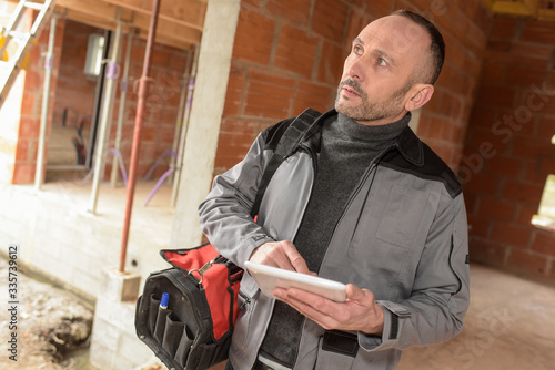 The contractor checks his notes on his tablet before starting working