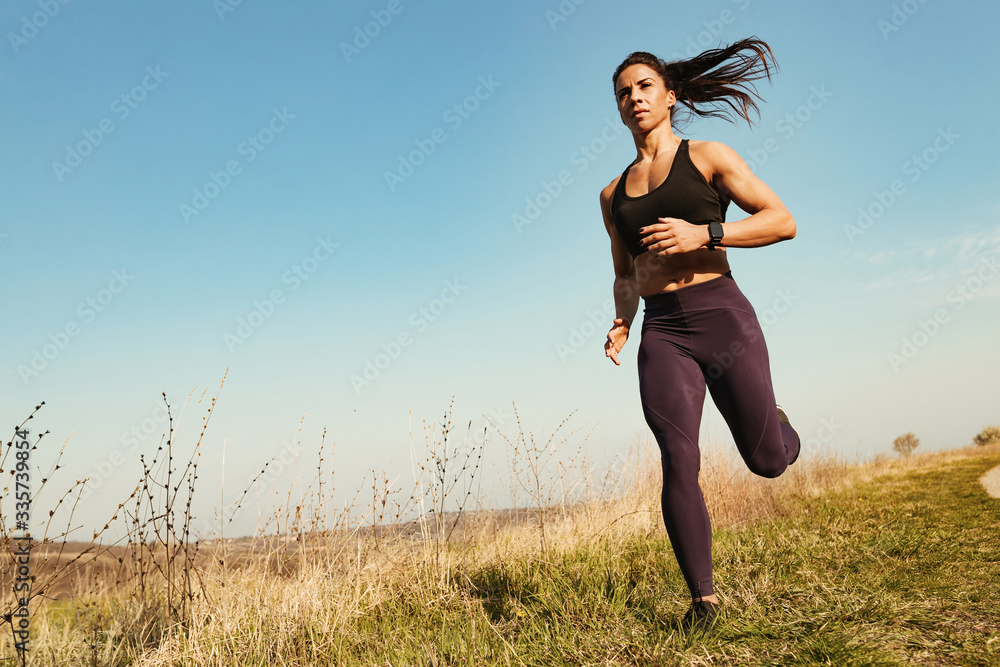 Below view of determined sportswoman running in nature. Below view of determined sportswoman running in nature.