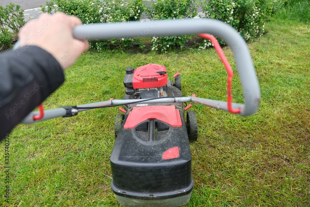 Working lawn mower on green lawn with trimmed grass Working lawn mower on green lawn with trimmed grass