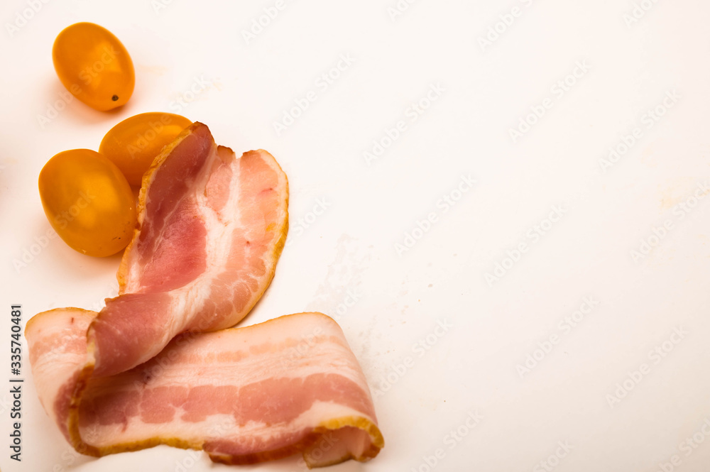 Bacon slices and tomatoes on a white background. Close up.