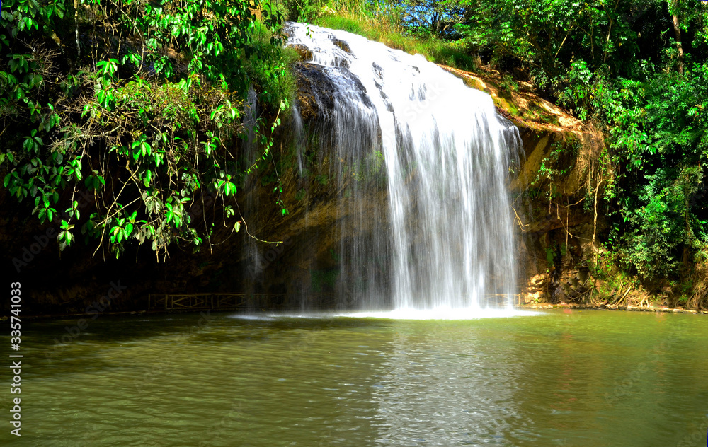 A beautiful waterfall in Vietnam in sunny warm summer day and a lot of green trees around