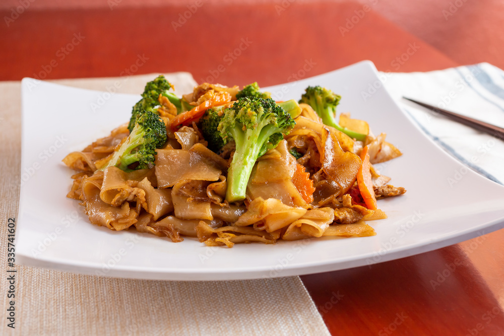 A view of a plate of Thai Pad See Ew in a restaurant or kitchen setting.