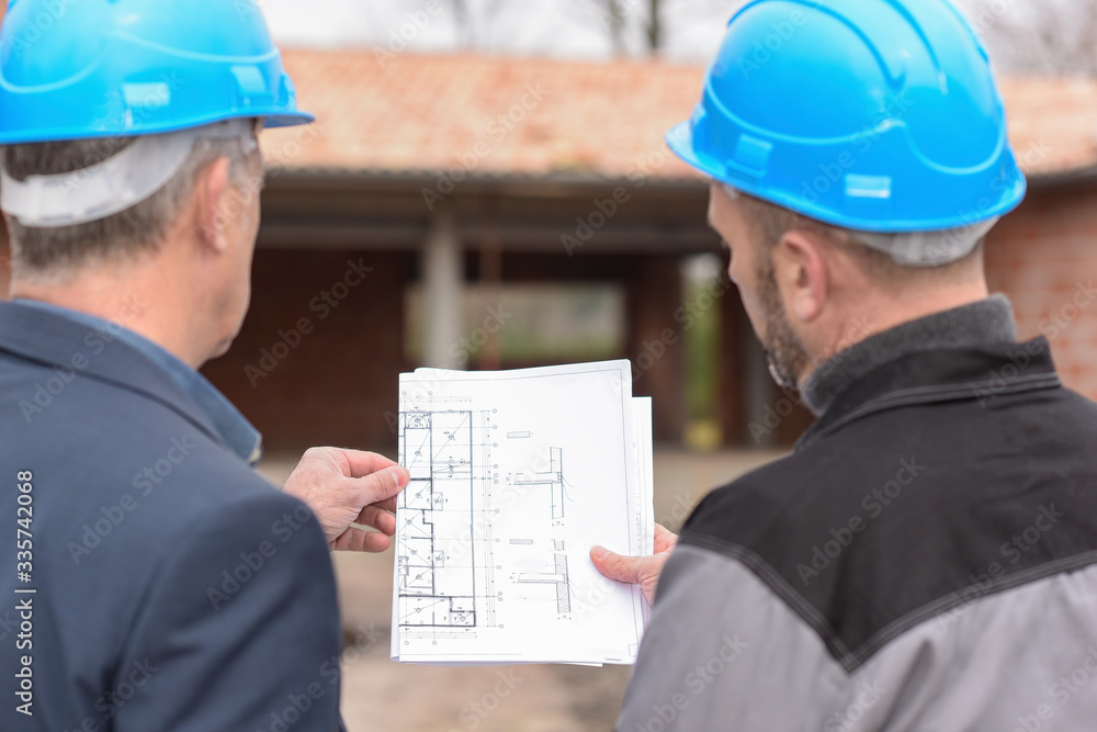 Architec and contractor checking a blue-print on a building site Architec and contractor checking a blue-print on a building site